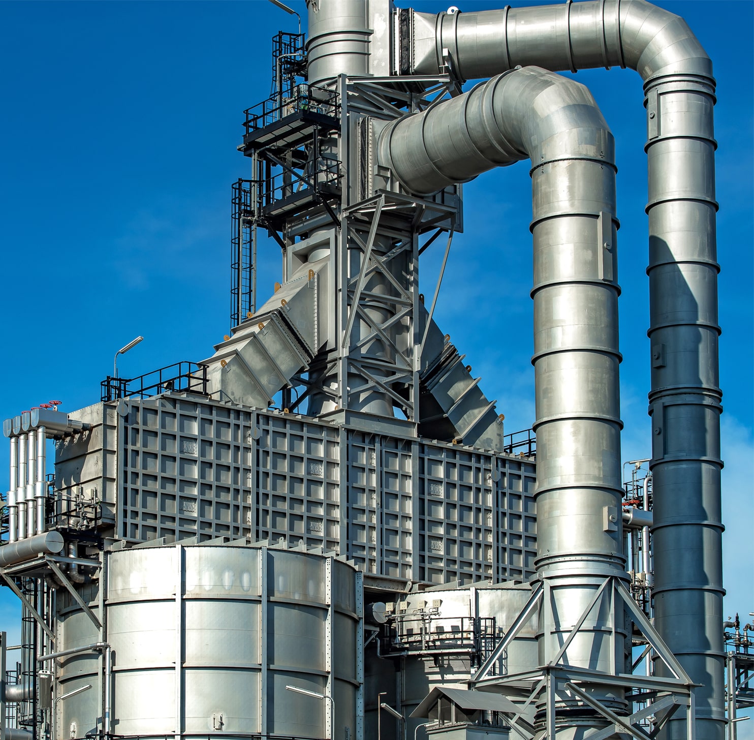 Close-up industrial view of pipelines in an oil and gas refinery tank zone.